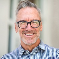 Man smiling with dentures wearing glasses 