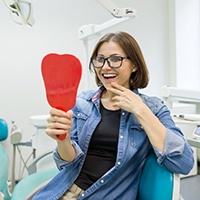 Woman smiling in dental chair looking in mirror