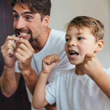 Father and son flossing their teeth together