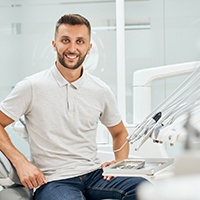 Man smiling in dental chair wearing grey polo