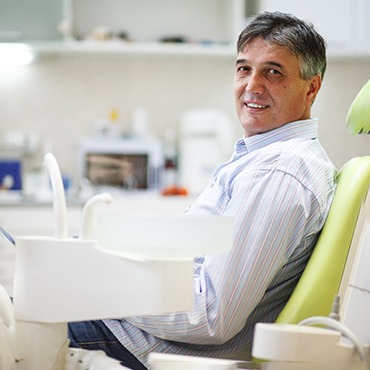 Older man sitting in dental chair and smiling