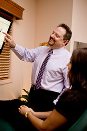 Doctor White pointing to screen speaking with cosmetic dentistry patient