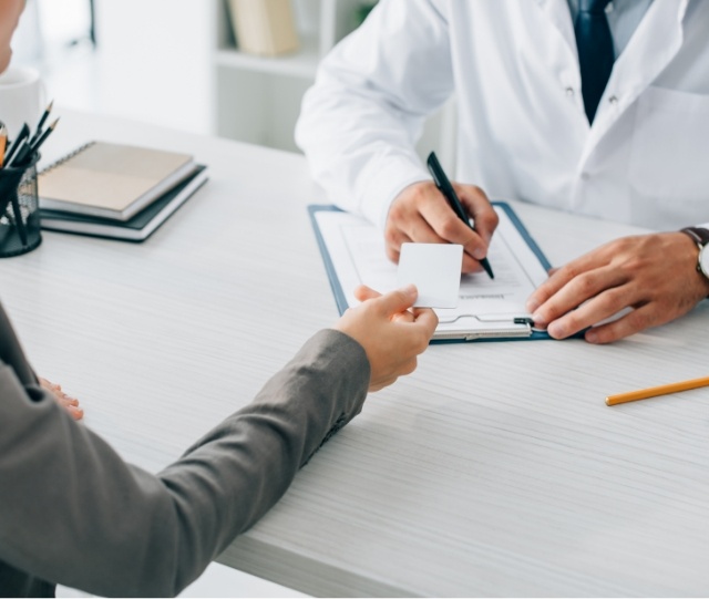 Dentist writing on clipboard while patient hands them a note