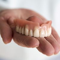 Close-up of hand holding dentures 