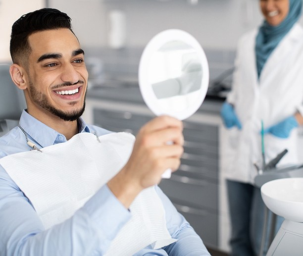 Man smiling at reflection in handheld mirror