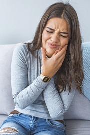 Woman on couch nursing a toothache