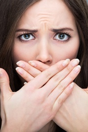 A woman holding her hands in front of her mouth because of bad breath