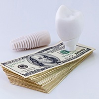 Model implant on money representing cost of dental implants in Asheville