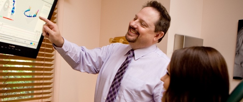 Asheville dentist Doctor John White pointing to monitor in dental office