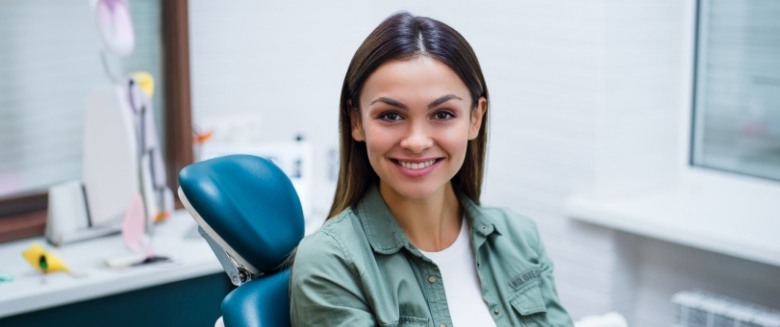 Woman in green jacket smiling in dental chair