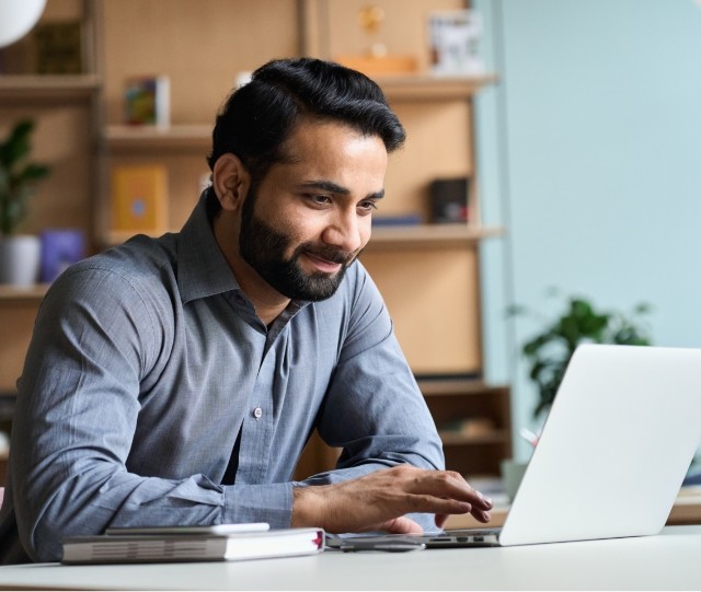 Smiling man in button up shirt working on laptop