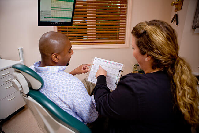 Photo of dental assistant consulting patient in operatory room