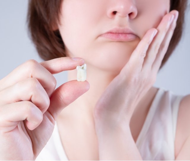 Woman rubbing jaw and holding a tooth