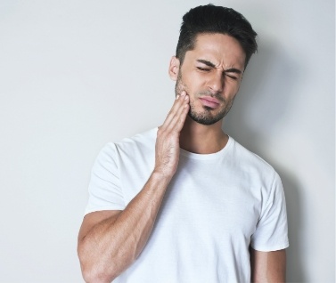 Man in white shirt rubbing his jaw