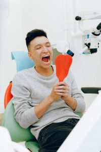 Man at dentist using a mirror to look in his mouth