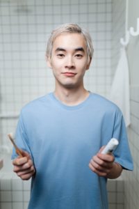 Young man holding toothbrush and toothpaste