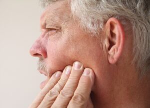 Man holding left side of jaw in pain.